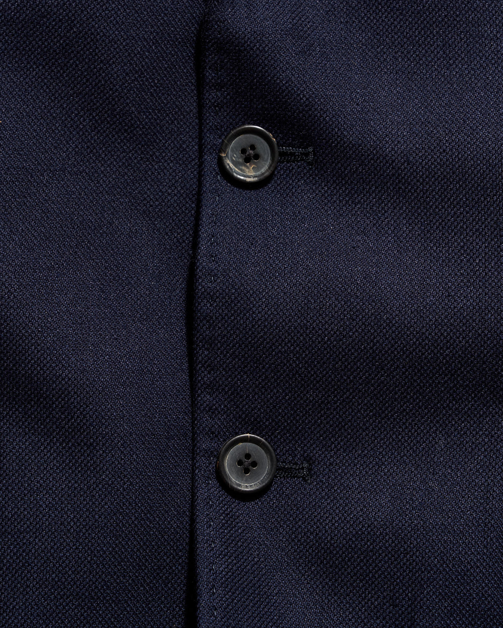 Close-up of a navy blue textured fabric with buttons