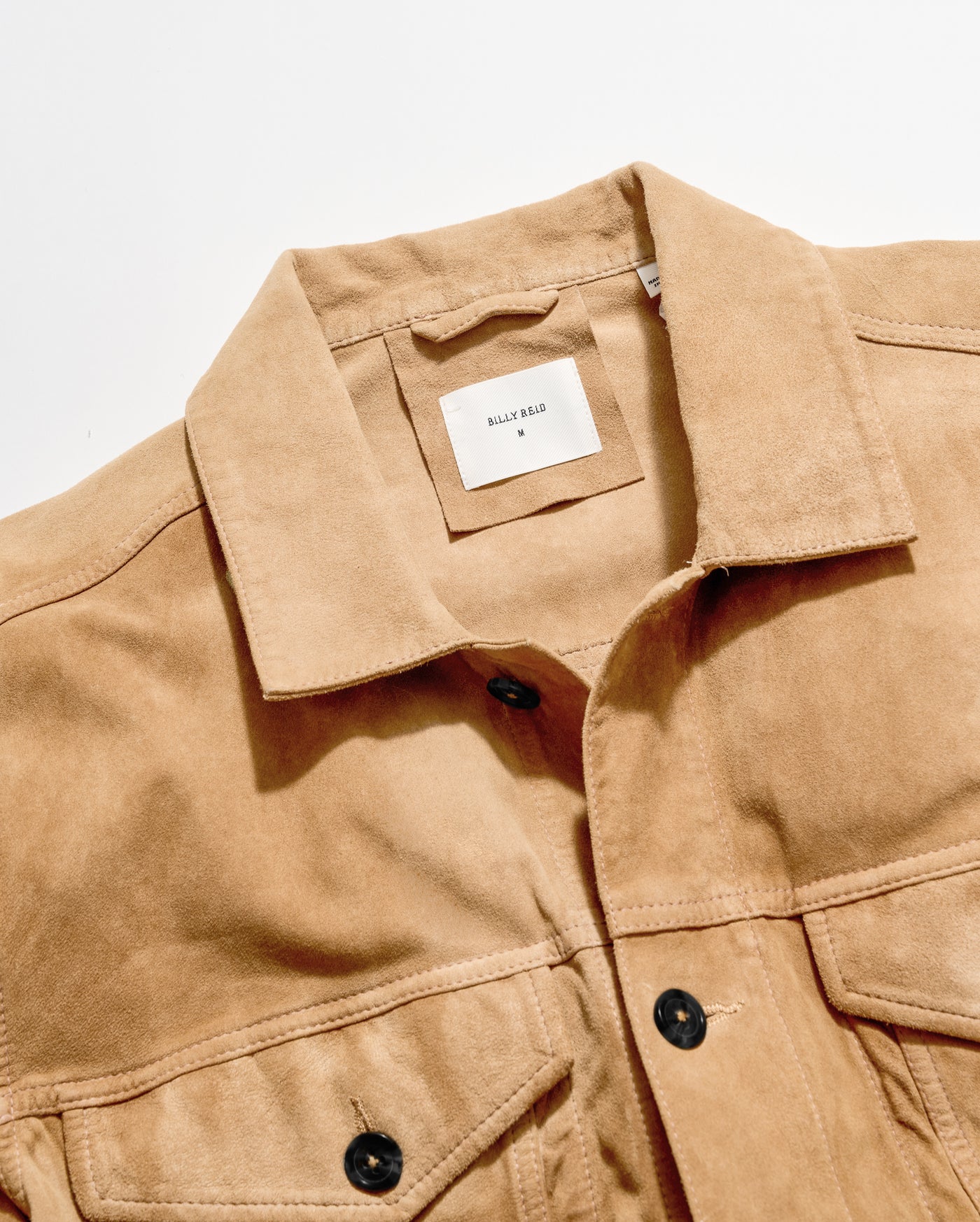 Close-up of a tan suede button-front jacket with a collar and a visible HALF BARE neck label, photographed on a clean white background.