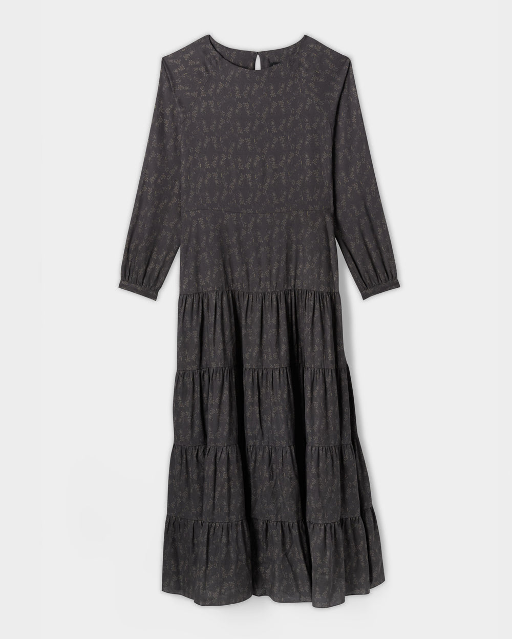 A long-sleeve, dark gray tiered midi dress with a subtle floral print and a round neckline, displayed on a plain white background.