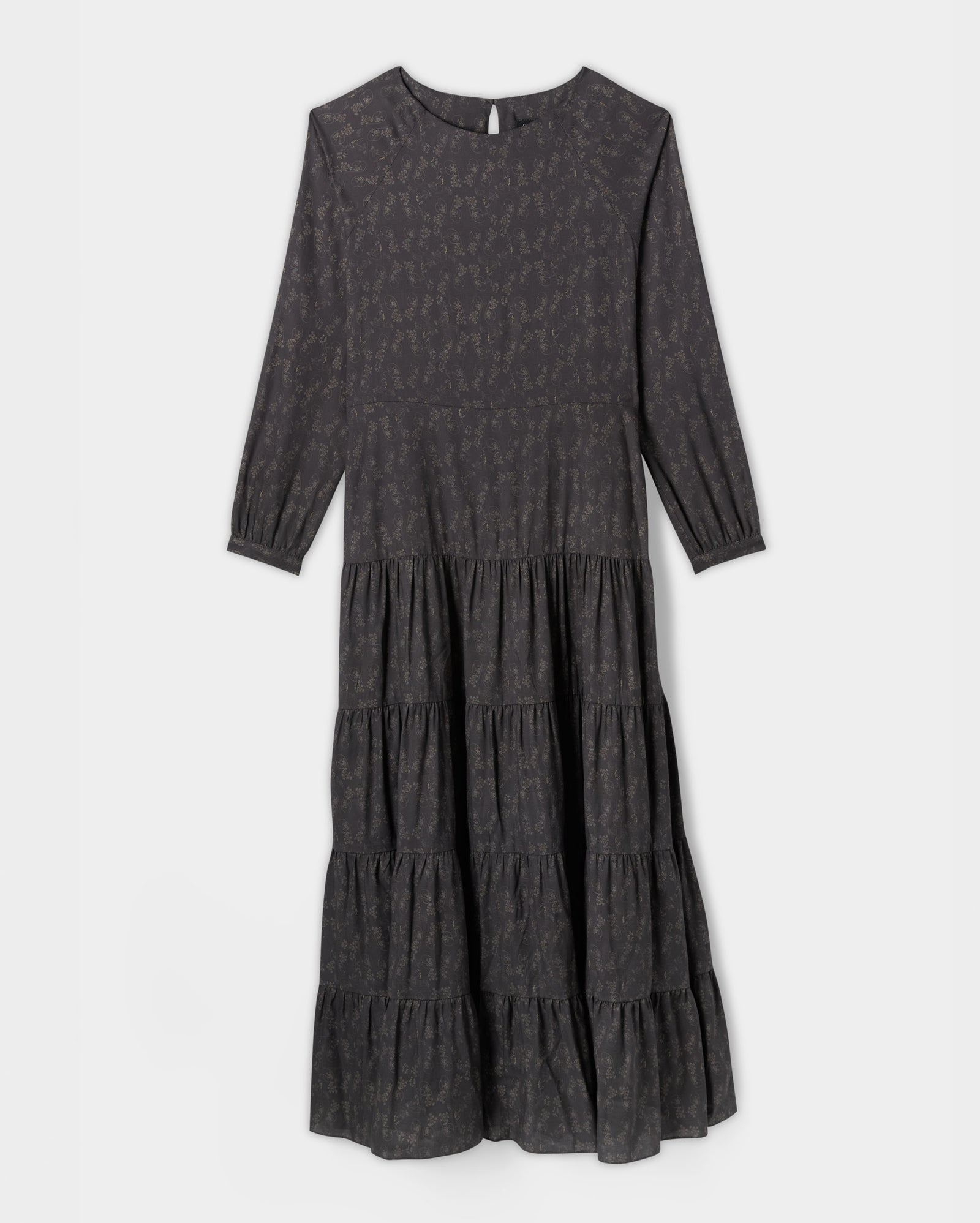 A long-sleeve, dark gray tiered midi dress with a subtle floral print and a round neckline, displayed on a plain white background.