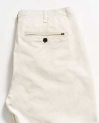A pair of neatly folded beige pants, showing the back side with a single welt pocket featuring a black button, against a plain white background.